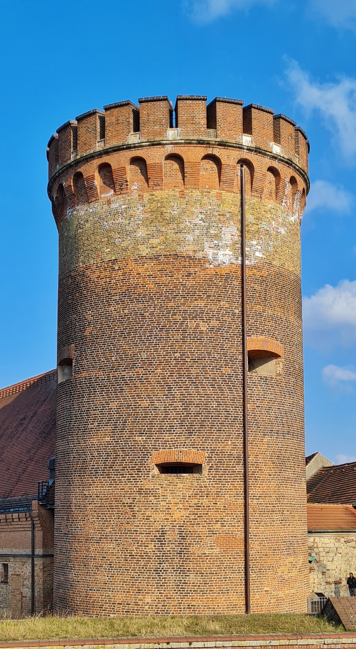 Die Vollaufnahme eijes Turms aus rotem Backstein mit Zinnen.
