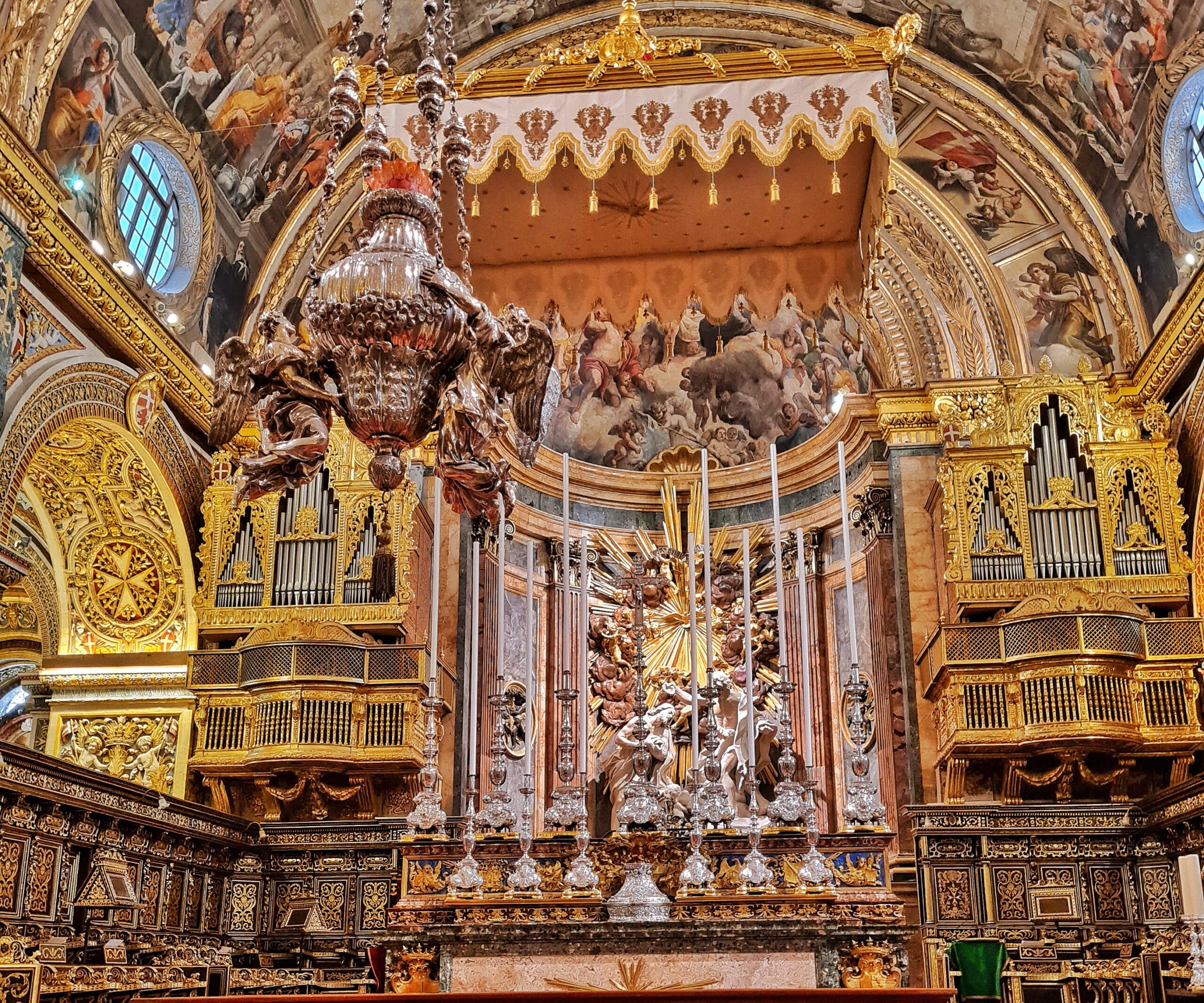 Blick auf den Altar mit dem Baldachin darüber und dem daneben hängenden Gefäß von vorne fotografiert. Links und rechts jeweils eine goldene Orgel.