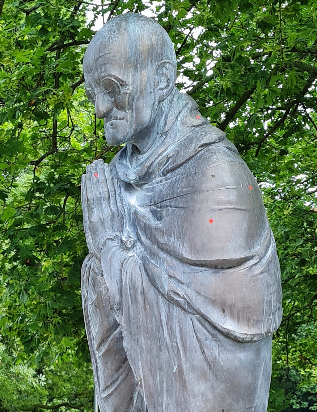 Eine Statue von der Seite. Es ist ein älterer Mann mit einer Nickelbrille. Die Hände hat er gefaltet.