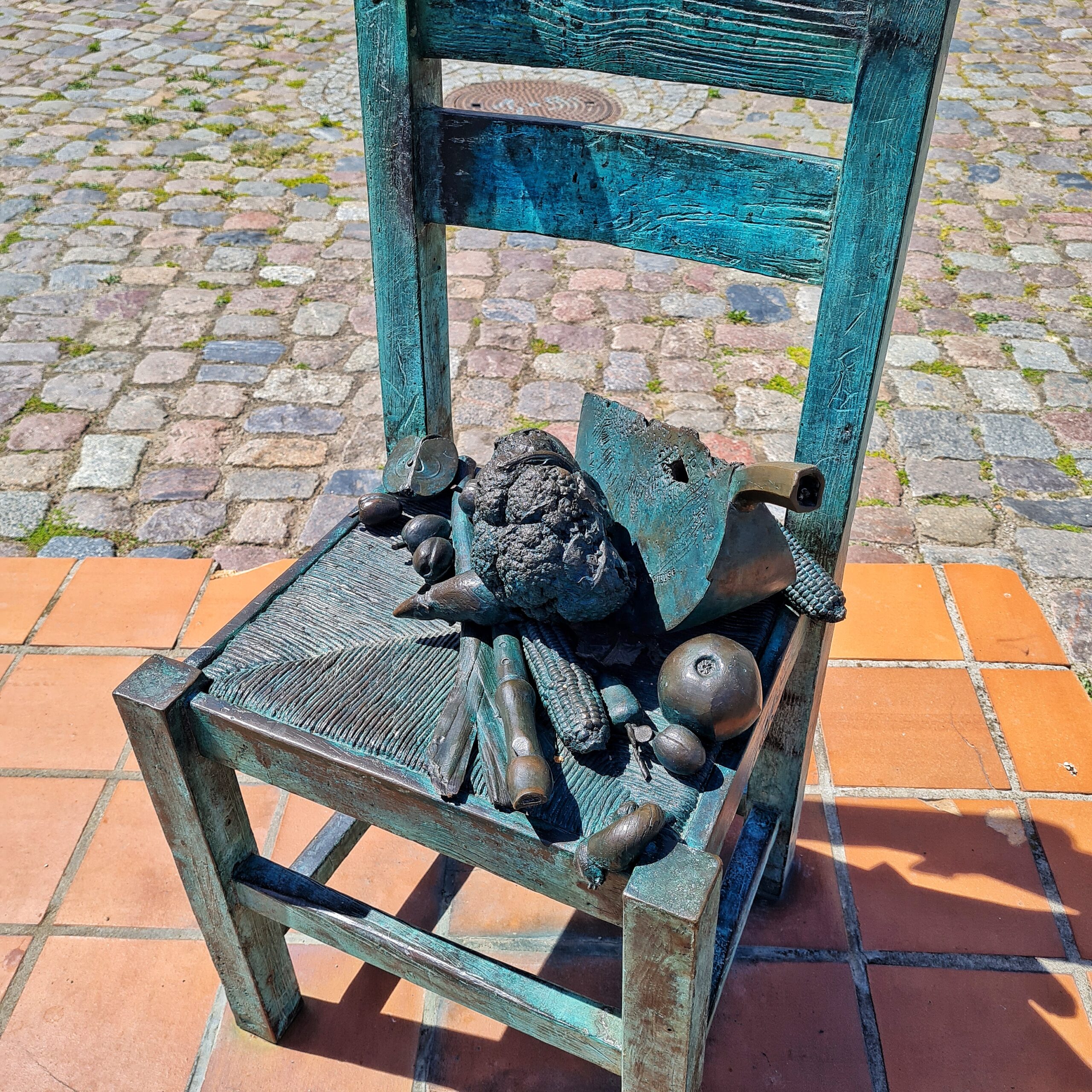 Ein Stuhl aus Metall, auf dem (ebenfalls aus Metall) Obst und Gemüse liegt.