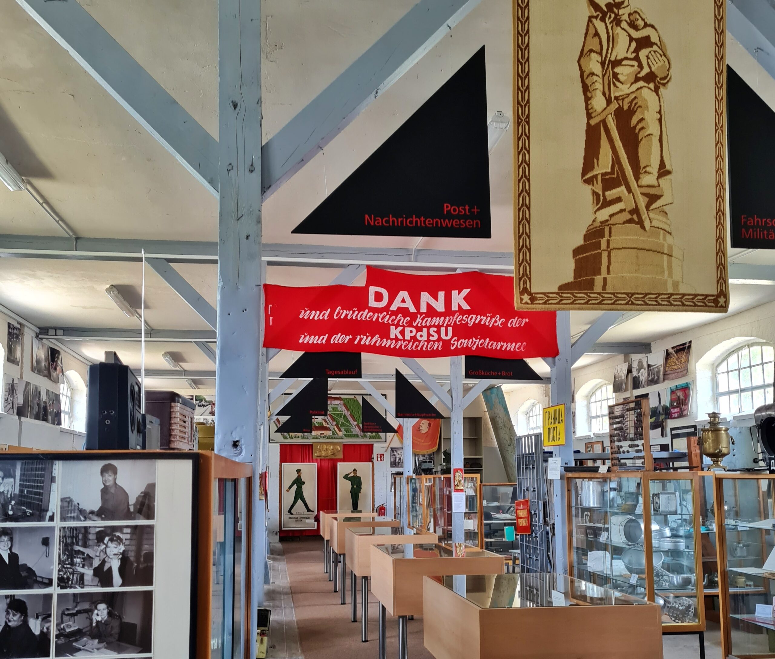 Ein Ausstellungsraum mit Vitrinen, Fotos, Bildern, Transparenten und Erklärungstafeln.