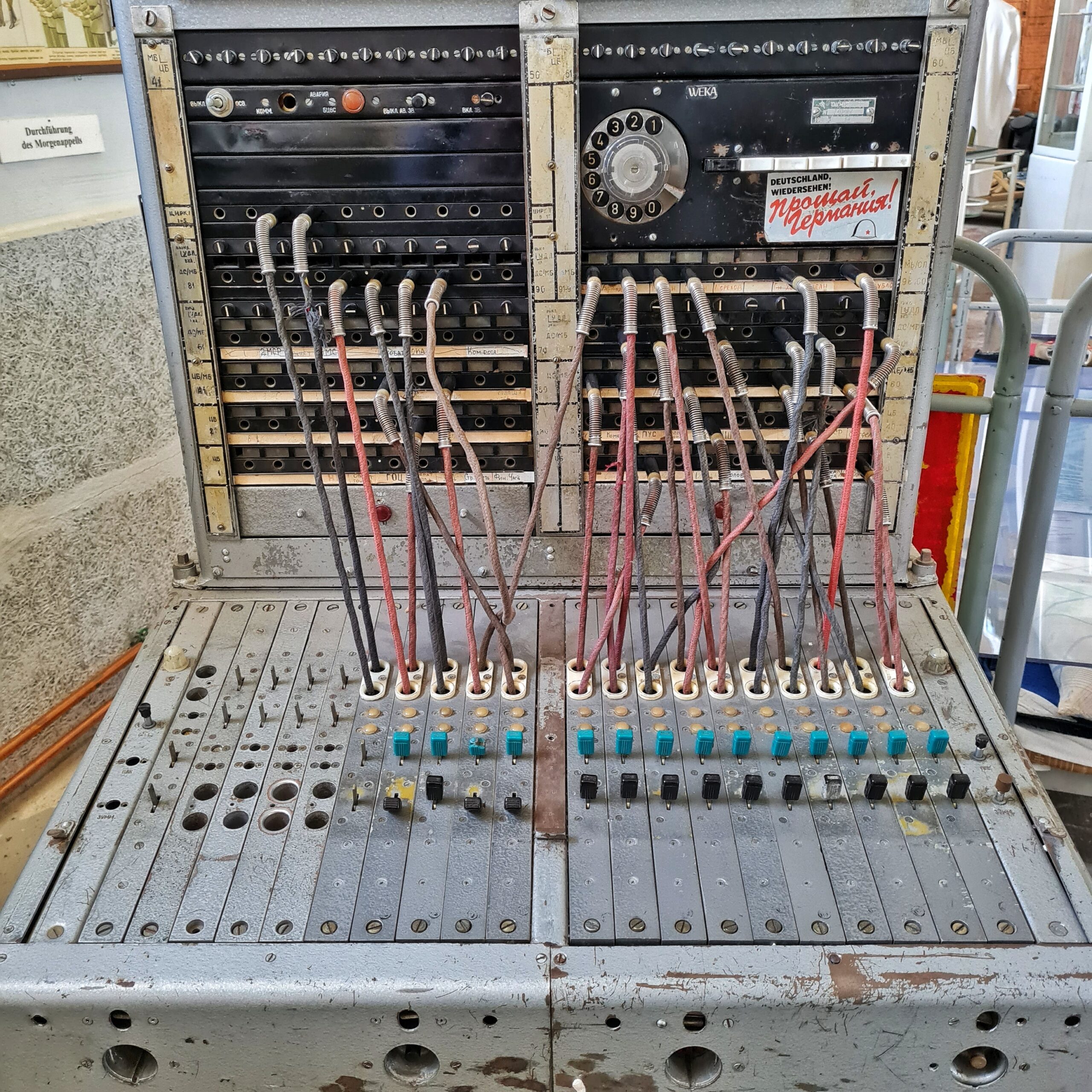 Eine alte Fernmeldeanlage. Kabel sind von der waagerechten zur senkrechten Schalterfläche gesteckt. Oben rechts ist eine Wählscheibe.