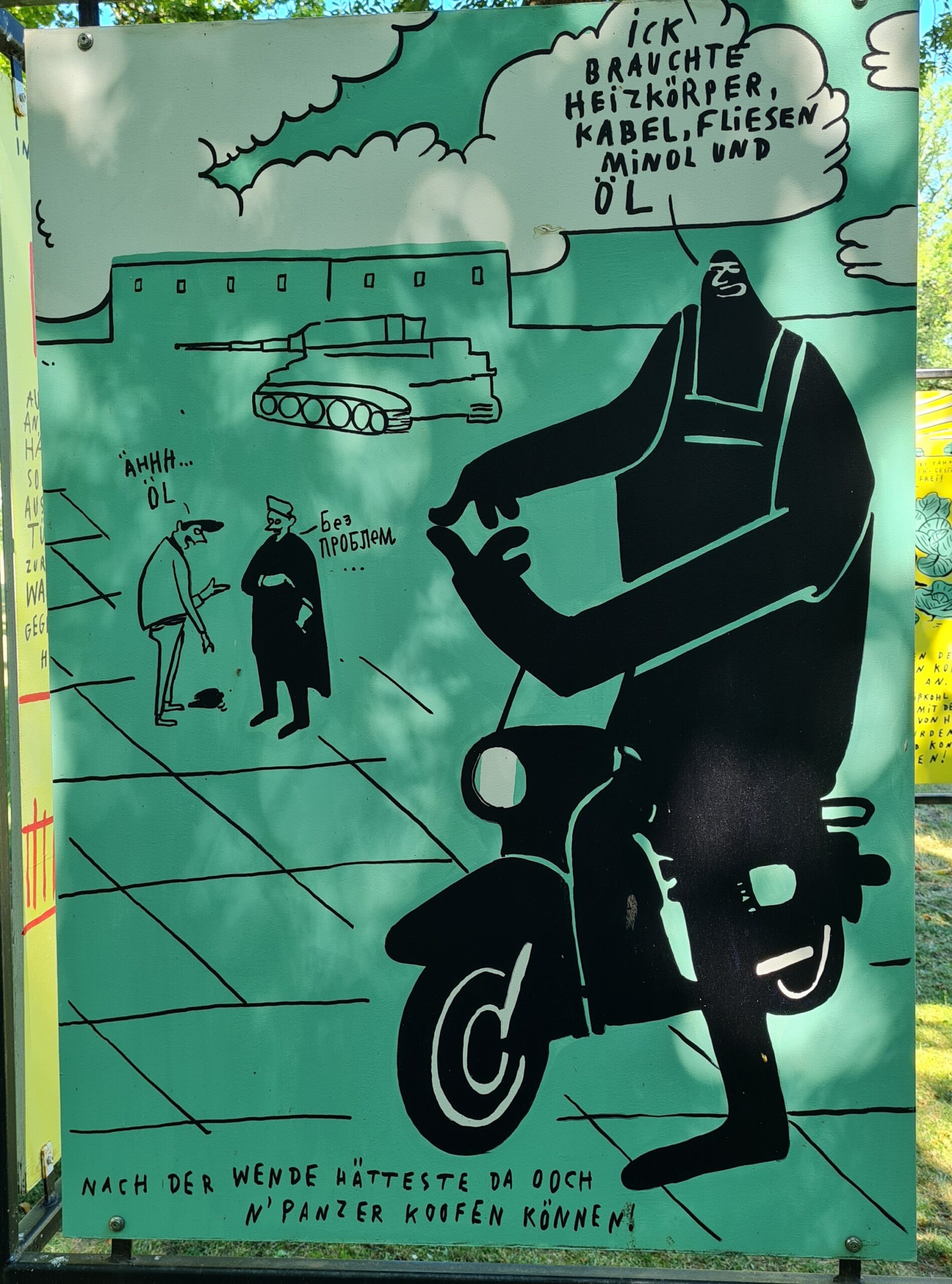 Auf dieser Tafel ist im Vordergrund ein großer schwarzgekleideter Mann auf einm Moped gezeichnet. Darüber die Sprechblase: Ich brauchte Heizkörper, Kabel, Fliesen, Minol und Öl. Links vin ihm, deutlich kleiner, zwei Männer. Der eine sagt "Ähh... Öl", der andere antwortet etwas auf russisch. Im Hintergrund Wolken, ein Geväude und davor ein Panzer. Ganz unten auf der Tafel steht: Nach der Wende hätteste da ooch n Panzer koofen können.
