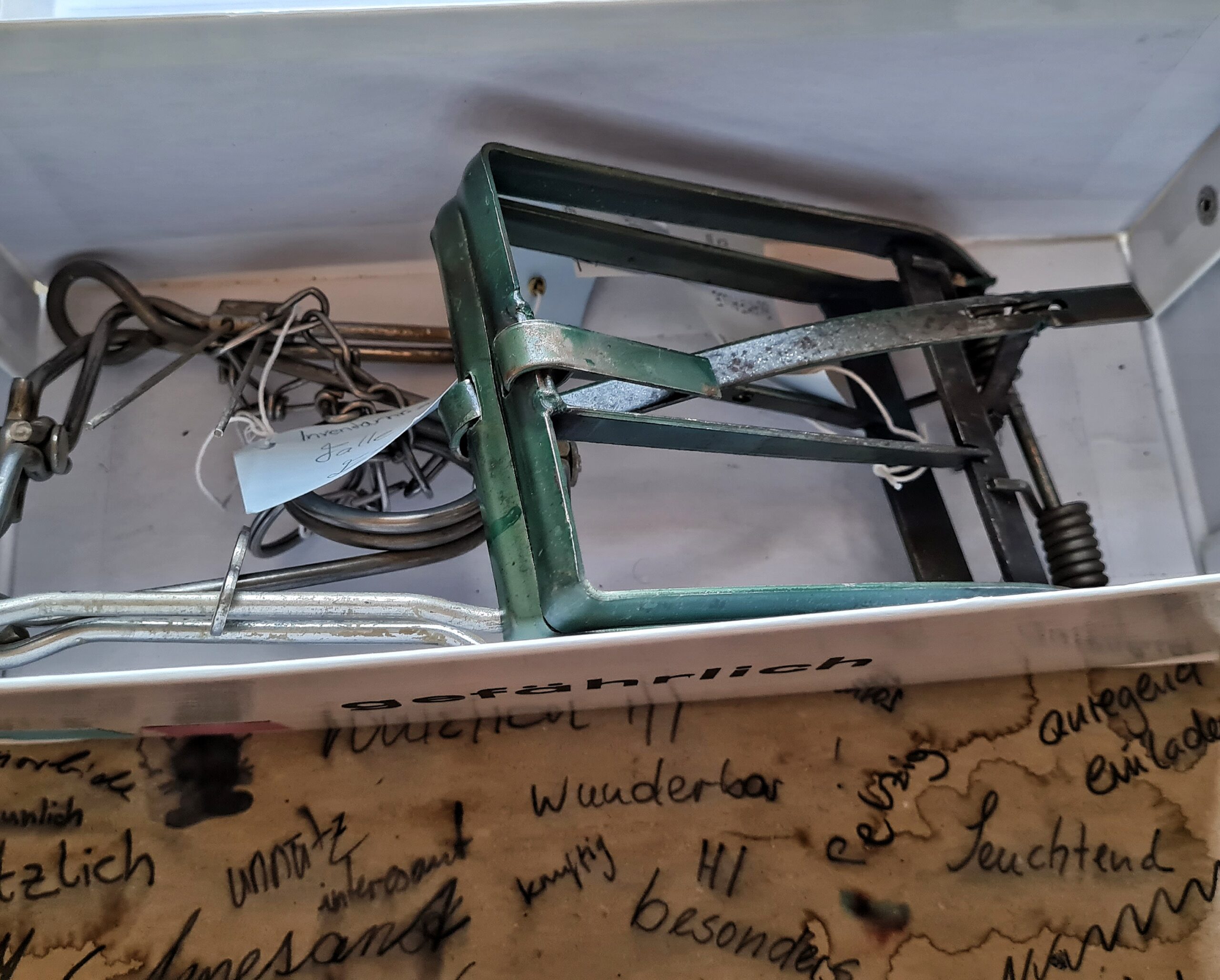 Der geöffnete weiße Karton mit der Aufschrift "gefährlich". Darin Tierfallen.