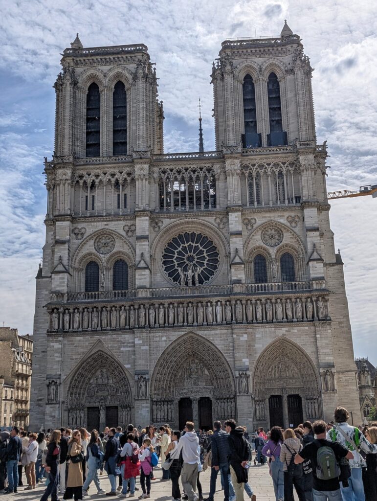 Blick auf die Kathedrale Notre-Dame de Paris mit Menschenmenge vor dem Eingang.