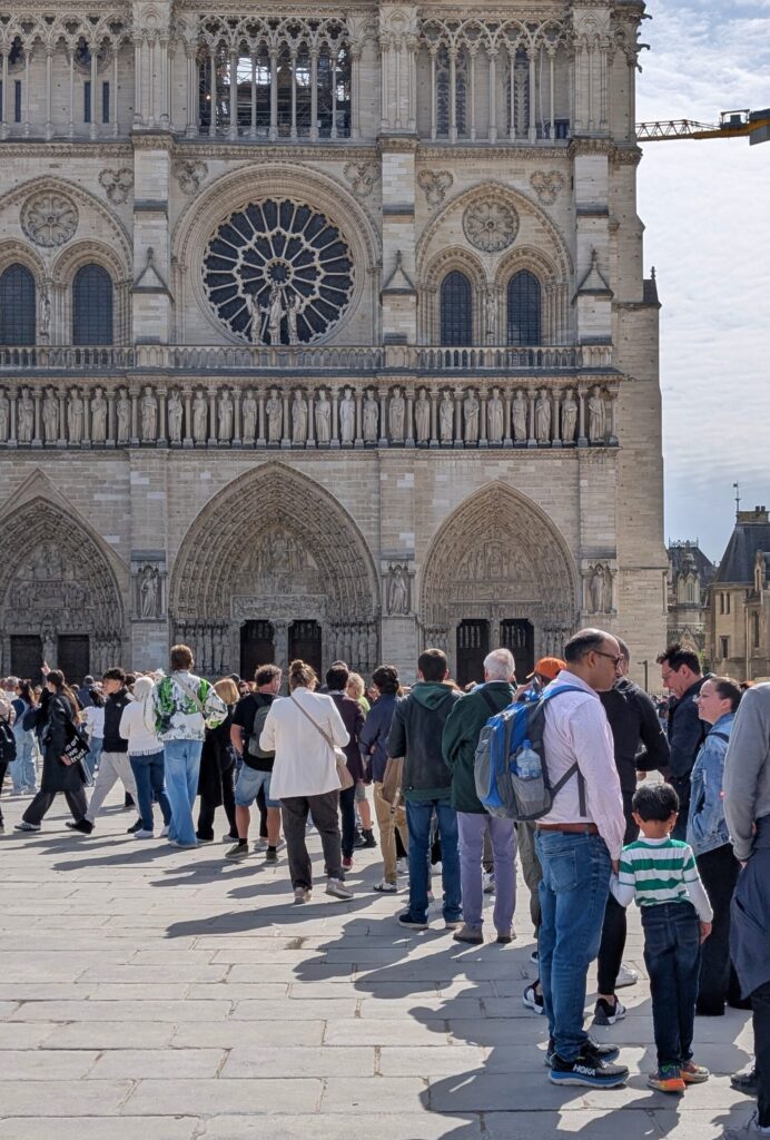 Warteschlange vor der Kathedrale Notre-Dame de Paris mit Blick auf die gotische Fassade und das Rosettenfenster.