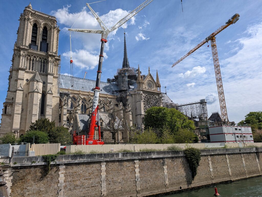 Die Kathedrale Notre-Dame de Paris während der Renovierungsarbeiten, mit Kranen und Baugerüsten im Hintergrund.
